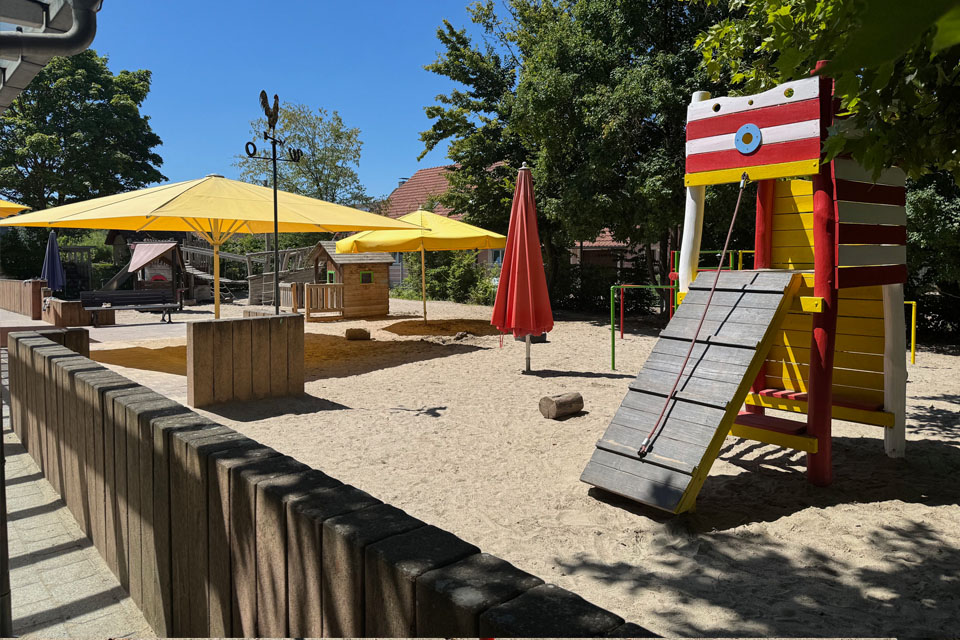 Außengelände Kita, Sandkasten mit Spielturm und Sonnenschirmen